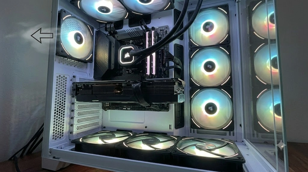 ピラーレスPCケースの側面ファンスペースに取り付けられた2基のRGBリバースファン。美しいブレード面がケース内側（左）を向き、鮮やかに発光している。ファン側面には、空気が右から左へ（ケース外から内へ）流れていることを示す、テキストなしの矢印が描かれている。ファン同士を連結する専用ケーブルとブラケットが見える。